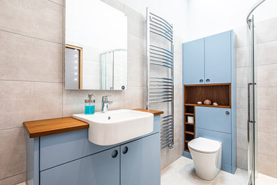 Esempio di una stanza da bagno per bambini minimalista di medie dimensioni con ante blu, piastrelle grigie, pareti grigie, top in legno, pavimento grigio, porta doccia scorrevole, top marrone e un lavabo
