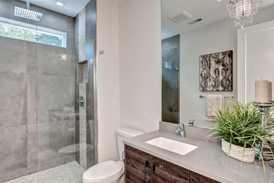 Example of a trendy gray tile and porcelain tile porcelain tile alcove shower design in Seattle with flat-panel cabinets, medium tone wood cabinets, a one-piece toilet, white walls, an undermount sink, wood countertops, a hinged shower door and gray countertops