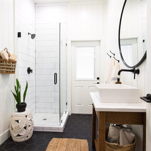 Example of a transitional white tile black floor corner shower design in Sacramento with furniture-like cabinets, medium tone wood cabinets, white walls, a vessel sink, a hinged shower door and white countertops