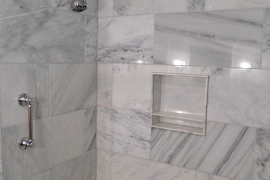 シカゴにある高級な中くらいなコンテンポラリースタイルのおしゃれなマスターバスルーム (レイズドパネル扉のキャビネット、白いキャビネット、アルコーブ型浴槽、シャワー付き浴槽	、分離型トイレ、白いタイル、大理石タイル、グレーの壁、大理石の床、アンダーカウンター洗面器、白い床、シャワーカーテン) の写真