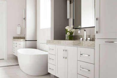 Diseño de cuarto de baño doble y a medida tradicional renovado con armarios estilo shaker, puertas de armario blancas, bañera exenta, paredes grises, suelo blanco y encimeras grises