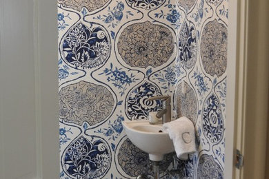 ボストンにある低価格の小さなトランジショナルスタイルのおしゃれな浴室 (一体型トイレ	、青い壁、セラミックタイルの床、壁付け型シンク、ベージュの床) の写真