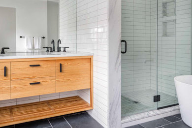Example of a mid-sized trendy master white tile and ceramic tile porcelain tile, gray floor, double-sink and exposed beam bathroom design in Boston with flat-panel cabinets, light wood cabinets, a one-piece toilet, white walls, an undermount sink, marble countertops, white countertops and a built-in vanity