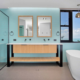 Photo of a contemporary master bathroom in Other with flat-panel cabinets, light wood cabinets, a freestanding tub, a curbless shower, blue tile, green tile, subway tile, blue walls, an integrated sink, grey floor and white benchtops.