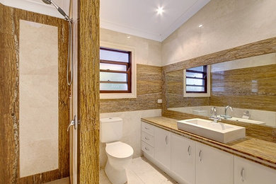 Inspiration för mellanstora moderna brunt badrum med dusch, med brun kakel, bruna väggar, beiget golv, luckor med upphöjd panel, en kantlös dusch, kakelplattor, kalkstensgolv och marmorbänkskiva