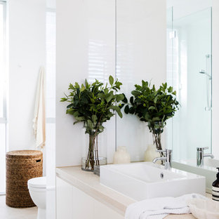 Design ideas for a mid-sized beach style master bathroom in Sydney with flat-panel cabinets, white cabinets, white tile, stone slab, white walls, ceramic floors, a vessel sink, beige floor and beige benchtops.