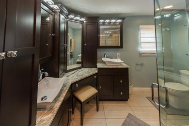 Example of a mid-sized trendy master gray tile and pebble tile porcelain tile and beige floor bathroom design in Indianapolis with a vessel sink, shaker cabinets, dark wood cabinets, granite countertops, a two-piece toilet, blue walls and a hinged shower door