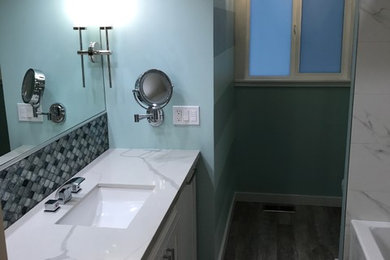 シアトルにある中くらいなコンテンポラリースタイルのおしゃれな浴室 (シェーカースタイル扉のキャビネット、白いキャビネット、アルコーブ型浴槽、シャワー付き浴槽	、分離型トイレ、白いタイル、磁器タイル、青い壁、セラミックタイルの床、アンダーカウンター洗面器、クオーツストーンの洗面台、グレーの床) の写真