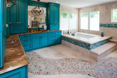 Inspiration for a large mediterranean master beige tile and ceramic tile pebble tile floor drop-in bathtub remodel in DC Metro with blue cabinets, recessed-panel cabinets, beige walls and granite countertops