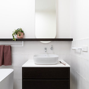 Design ideas for a contemporary bathroom in Melbourne with flat-panel cabinets, black cabinets, a freestanding tub, white tile, white walls, a vessel sink, white floor, white benchtops, a single vanity and a floating vanity.