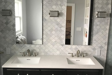 Ispirazione per una stanza da bagno padronale classica di medie dimensioni con ante lisce, ante nere, pareti grigie, lavabo sottopiano, top in superficie solida e top bianco
