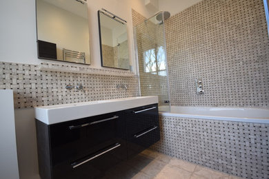 Photo of a large contemporary family bathroom in London with a built-in bath, a shower/bath combination, a wall mounted toilet, ceramic flooring, a wall-mounted sink and a hinged door.