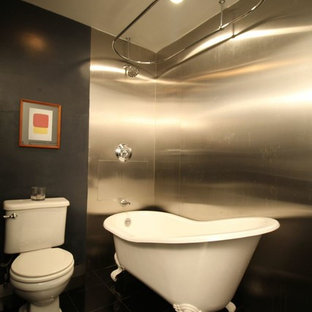 Design ideas for a mid-sized modern master bathroom in New York with a pedestal sink, furniture-like cabinets, dark wood cabinets, solid surface benchtops, a claw-foot tub, a shower/bathtub combo, a two-piece toilet, gray tile, metal tile, beige walls and marble floors.