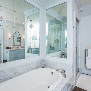 Ejemplo de cuarto de baño principal, tradicional renovado, grande, con armarios con rebordes decorativos, puertas de armario grises, bañera encastrada, ducha empotrada, paredes grises, suelo de madera oscura, lavabo bajoencimera, encimera de mármol y ducha con puerta con bisagras