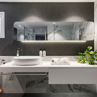 Design ideas for a contemporary bathroom in Brisbane with flat-panel cabinets, white cabinets, a freestanding tub, gray tile, white tile, grey walls, a vessel sink, grey floor and white benchtops.