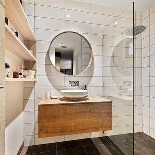 Photo of a small contemporary master wet room bathroom in Melbourne with raised-panel cabinets, medium wood cabinets, a two-piece toilet, white tile, ceramic tile, multi-coloured walls, ceramic floors, a vessel sink, wood benchtops, black floor, an open shower and brown benchtops.