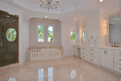 Large transitional master beige tile and stone tile marble floor and beige floor bathroom photo in Miami with an undermount sink, raised-panel cabinets, white cabinets, marble countertops, white walls, a two-piece toilet and a hinged shower door