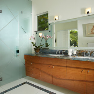 Photo of a small contemporary 3/4 bathroom in Miami with an undermount sink, furniture-like cabinets, light wood cabinets, marble benchtops, a drop-in tub, a double shower, a one-piece toilet, beige tile, glass tile, white walls and marble floors.