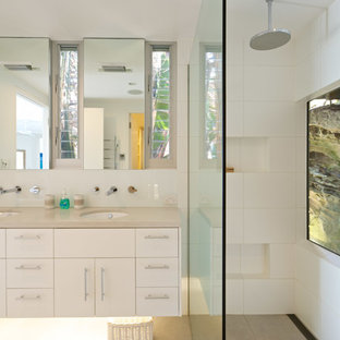 Photo of a mid-sized beach style bathroom in Sydney with white cabinets, white tile, ceramic tile, white walls, an undermount sink, engineered quartz benchtops, beige floor, an open shower, beige benchtops, flat-panel cabinets and a curbless shower.
