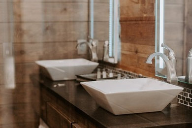 Imagen de cuarto de baño principal rural grande con puertas de armario de madera en tonos medios, bañera encastrada, baldosas y/o azulejos marrones, paredes marrones, lavabo sobreencimera, encimera de cuarzo compacto y encimeras negras