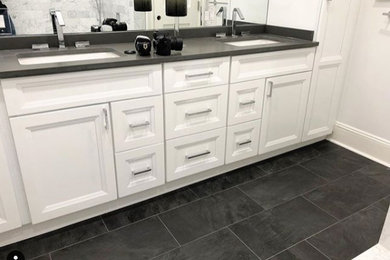 Bathroom - transitional black floor bathroom idea in New York with recessed-panel cabinets, white cabinets, white walls and gray countertops