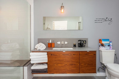 Inspiration for a mid-sized contemporary master wet room remodel in Los Angeles with flat-panel cabinets, medium tone wood cabinets, a two-piece toilet, gray walls, an undermount sink, quartz countertops and gray countertops