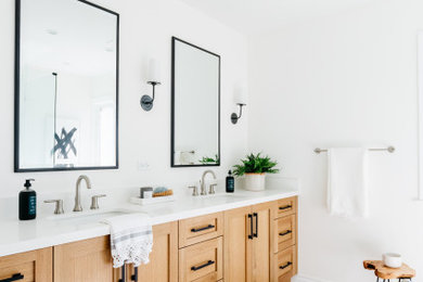 Rural ensuite bathroom in Los Angeles with shaker cabinets, light wood cabinets, a corner shower, white tiles, white walls, porcelain flooring, a submerged sink, engineered stone worktops, grey floors and white worktops.