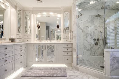 Идея дизайна: большая главная ванная комната в стиле неоклассика (современная классика) с врезной раковиной, фасадами с утопленной филенкой, белыми фасадами, мраморной столешницей, угловым душем, белой плиткой, каменной плиткой, серыми стенами и мраморным полом