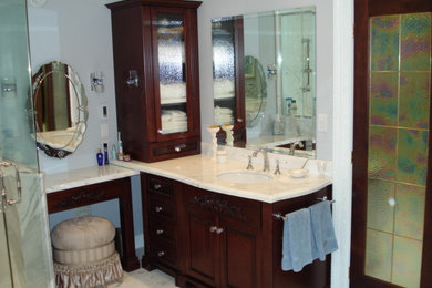 Diseño de cuarto de baño principal tradicional renovado grande con armarios tipo mueble, ducha esquinera, suelo de mármol, lavabo bajoencimera, encimera de mármol, ducha con puerta con bisagras, puertas de armario de madera en tonos medios, bañera exenta, paredes azules y suelo blanco