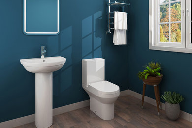 Modelo de cuarto de baño infantil contemporáneo de tamaño medio con sanitario de dos piezas, paredes azules, suelo laminado, lavabo con pedestal y suelo marrón