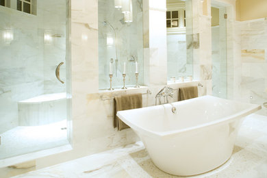 Cette photo montre une grande salle de bain principale chic avec une baignoire indépendante, un placard à porte affleurante, des portes de placard blanches, un carrelage gris, des carreaux de céramique, un mur beige, un sol en carrelage de céramique, un lavabo posé et un plan de toilette en granite.