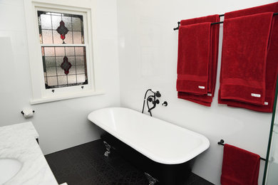Идея дизайна: главная ванная комната среднего размера в викторианском стиле с фасадами в стиле шейкер, черными фасадами, ванной на ножках, угловым душем, раздельным унитазом, белой плиткой, керамической плиткой, белыми стенами, полом из керамической плитки, накладной раковиной, мраморной столешницей, черным полом и душем с распашными дверями