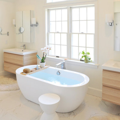 Mid-sized trendy master white tile and ceramic tile marble floor freestanding bathtub photo in Providence with light wood cabinets, white walls, an integrated sink, flat-panel cabinets and a one-piece toilet