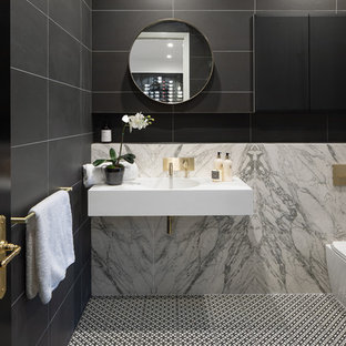 Photo of a contemporary 3/4 bathroom in Brisbane with a corner shower, a one-piece toilet, black tile, gray tile, a wall-mount sink, multi-coloured floor, a hinged shower door and white benchtops.