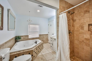 ヒューストンにあるトラディショナルスタイルのおしゃれな浴室 (コーナー型浴槽、オープン型シャワー、分離型トイレ、トラバーチンタイル、コンソール型シンク、シャワーカーテン) の写真