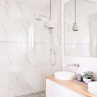 Photo of a contemporary bathroom in Brisbane with flat-panel cabinets, white cabinets, an alcove shower, white tile, a vessel sink, wood benchtops, grey floor and beige benchtops.
