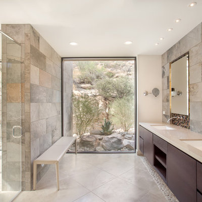 Inspiration for a large contemporary master glass tile and gray tile limestone floor walk-in shower remodel in Phoenix with flat-panel cabinets, dark wood cabinets, an undermount sink, solid surface countertops and gray walls