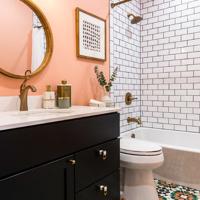 Mid-sized trendy 3/4 white tile and subway tile multicolored floor and ceramic tile bathroom photo in DC Metro with recessed-panel cabinets, black cabinets, pink walls, an undermount sink, white countertops, a two-piece toilet and solid surface countertops