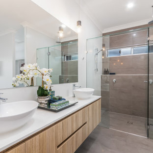 Inspiration for a large beach style 3/4 bathroom in Brisbane with flat-panel cabinets, light wood cabinets, an alcove shower, gray tile, white walls, a vessel sink, grey floor, a hinged shower door, white benchtops, a double vanity and a floating vanity.