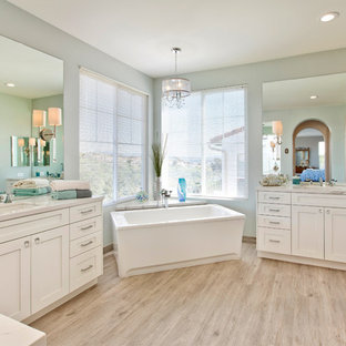 Imagen de cuarto de baño principal, marinero, grande, con armarios estilo shaker, puertas de armario blancas, bañera exenta, sanitario de dos piezas, baldosas y/o azulejos de porcelana, paredes azules, suelo de baldosas de porcelana, lavabo bajoencimera, encimera de cuarzo compacto y suelo beige