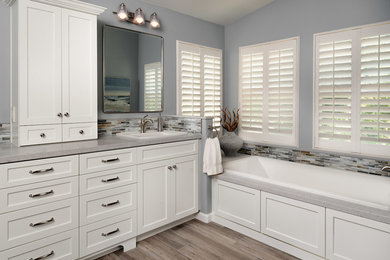 Example of a mid-sized beach style master blue tile and glass tile porcelain tile and multicolored floor bathroom design in San Diego with shaker cabinets, white cabinets, a one-piece toilet, blue walls, a drop-in sink, quartz countertops, a hinged shower door and gray countertops