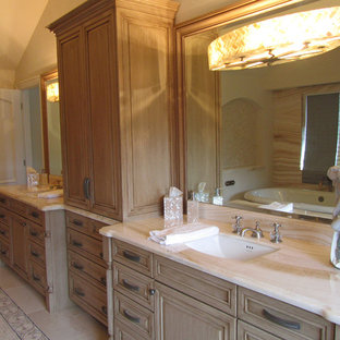 Large traditional master bathroom in Sacramento with raised-panel cabinets, distressed cabinets, a freestanding tub, an alcove shower, a one-piece toilet, beige tile, porcelain tile, beige walls, porcelain floors, an undermount sink and onyx benchtops.