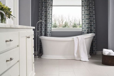 Foto de cuarto de baño clásico con armarios estilo shaker, puertas de armario blancas, bañera exenta, paredes grises, suelo vinílico, encimera de mármol y suelo blanco
