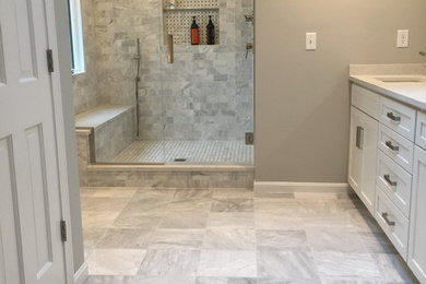 Example of a large trendy master gray tile and marble tile marble floor alcove shower design in Boston with flat-panel cabinets, white cabinets, a two-piece toilet, gray walls, an undermount sink and quartz countertops