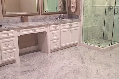 Corner shower - traditional master white tile marble floor corner shower idea in Houston with white cabinets, marble countertops and an undermount sink