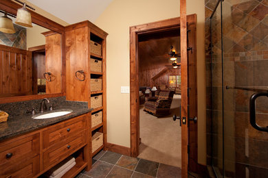 Small mountain style 3/4 brown tile and stone tile slate floor alcove shower photo in Minneapolis with an undermount sink, recessed-panel cabinets, medium tone wood cabinets, granite countertops, a two-piece toilet and beige walls