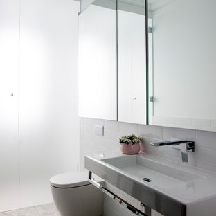 Design ideas for a mid-sized traditional wet room bathroom in Sydney with glass-front cabinets, a wall-mount toilet, white tile, subway tile, white walls, marble floors, a wall-mount sink, white floor, a hinged shower door and white benchtops.