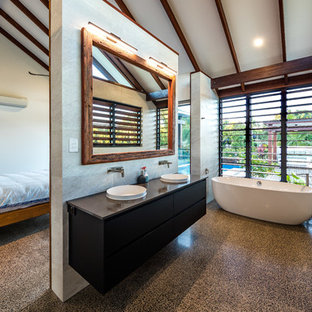 Tropical master bathroom in Cairns with flat-panel cabinets, black cabinets, a freestanding tub, gray tile, grey walls, concrete floors, a drop-in sink, grey floor and grey benchtops.