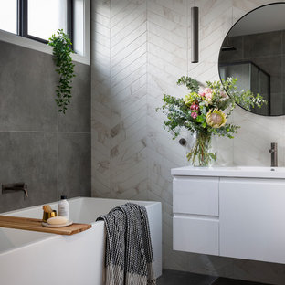 Photo of a contemporary bathroom in Canberra - Queanbeyan with white cabinets, gray tile, beige tile, porcelain tile, porcelain floors, an integrated sink, grey floor, flat-panel cabinets, an alcove tub and white benchtops.