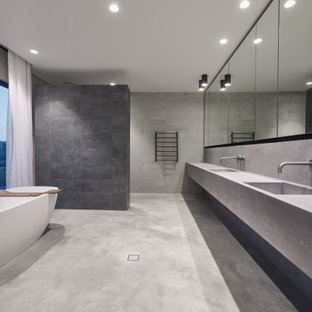 Inspiration for a large modern master bathroom in Perth with grey cabinets, a freestanding tub, gray tile, stone slab, grey walls, concrete floors, concrete benchtops, grey floor, an open shower, grey benchtops, a double vanity, a curbless shower, an integrated sink and a floating vanity.